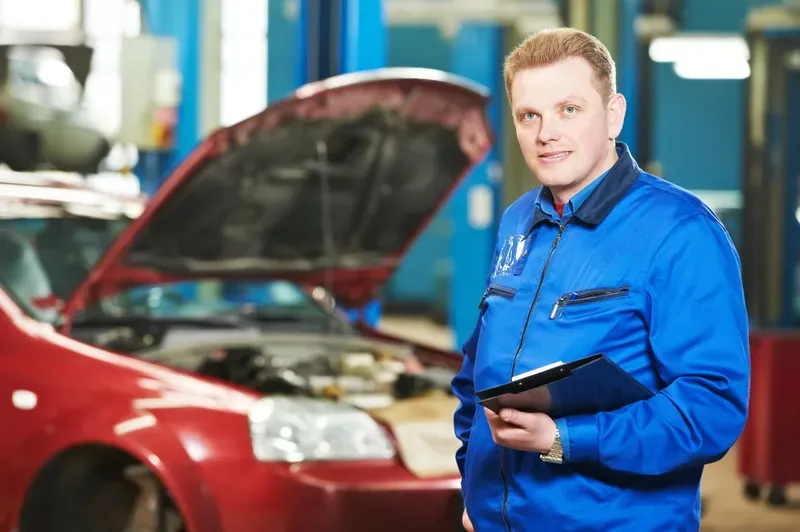 Consilier service auto cu deviz in mana, langa o masina in atelier
